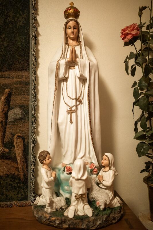 Statue depicting Virgin Mary with children in prayer, symbolizing devotion and faith.